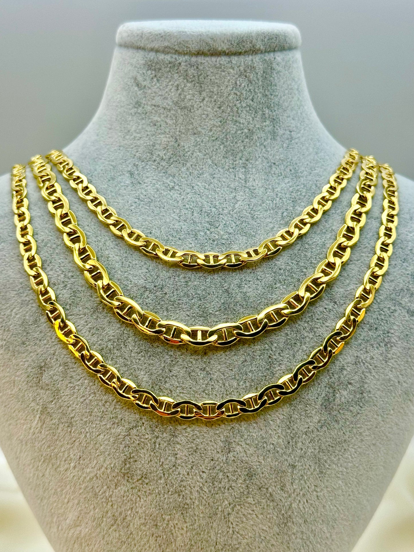A 14K gold anchor chain necklace displayed on a mannequin bust, featuring uniformly sized repeating oval links arranged in alternating horizontal and vertical directions with a vertical bar at each link center.