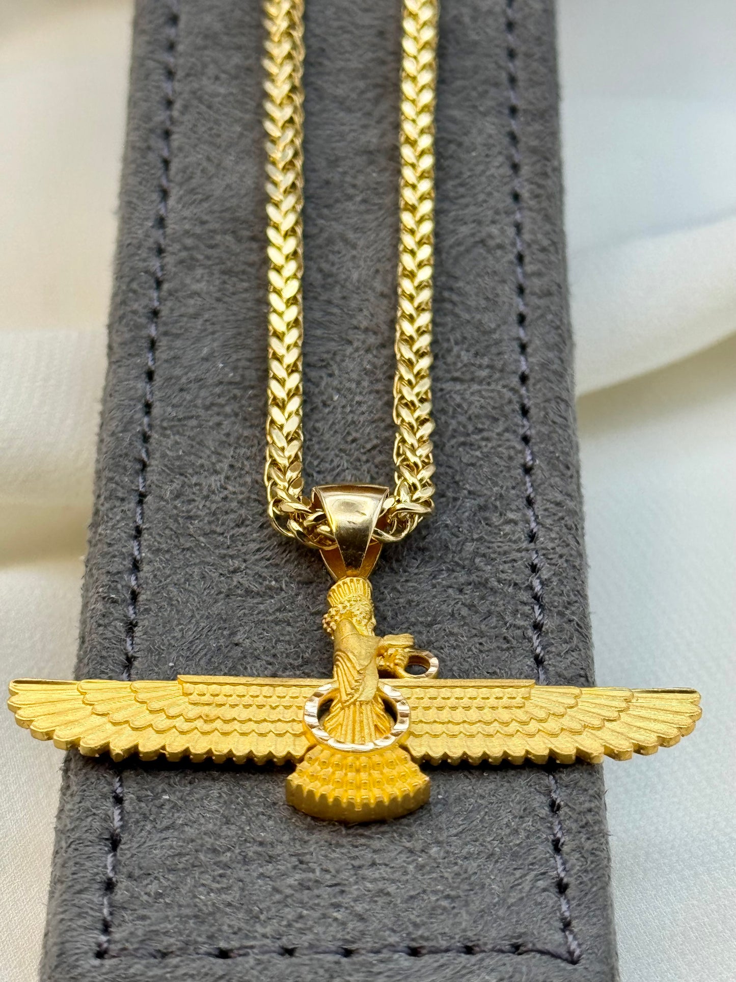 Gold necklace with a pendant on a gray textured background