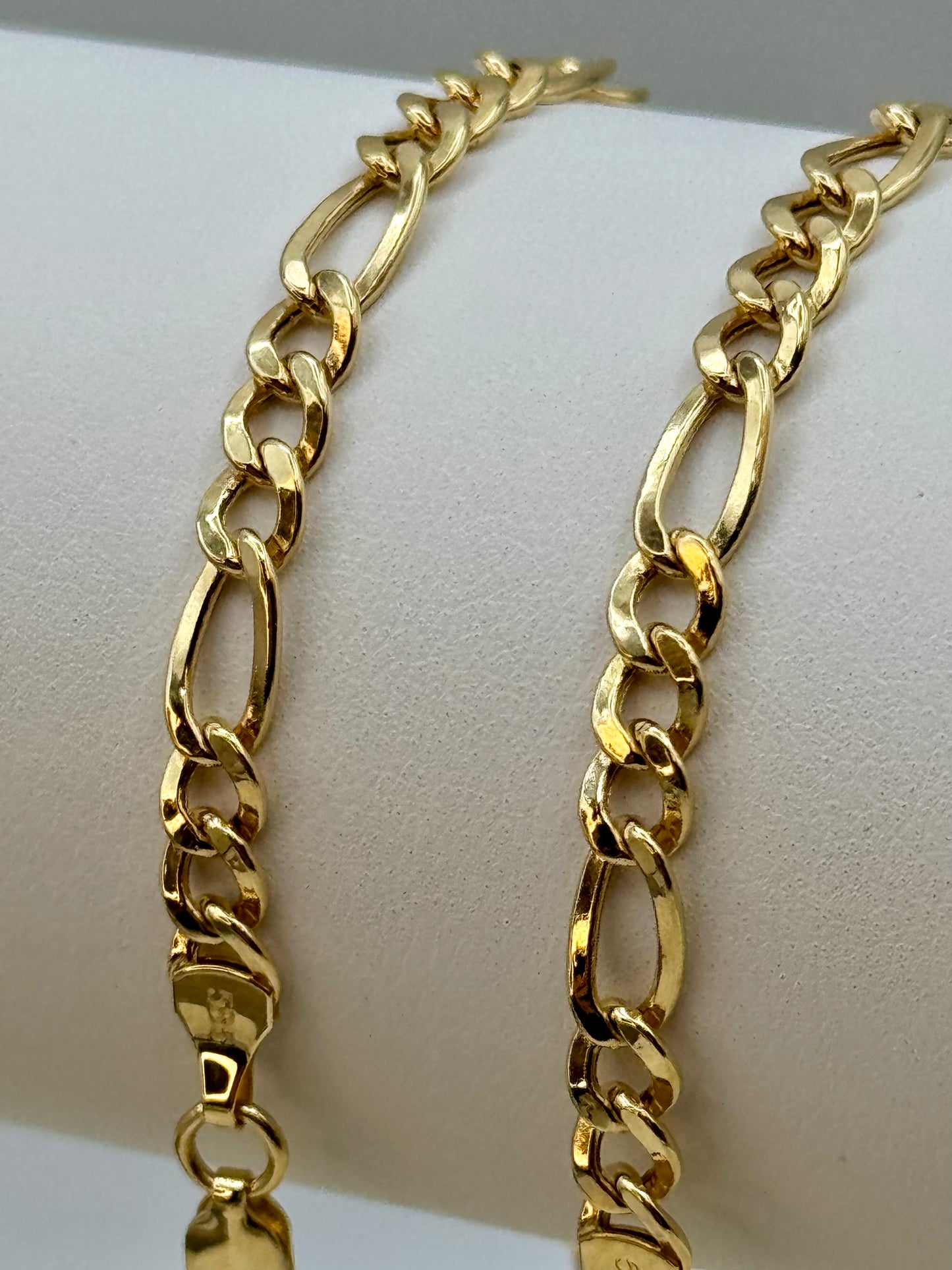Gold chain bracelet on a white mannequin arm