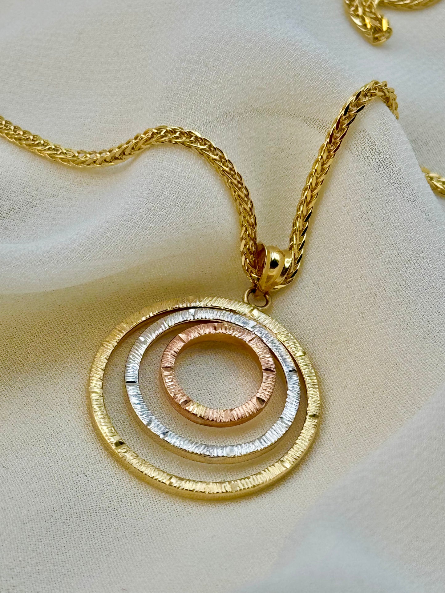 A 14k gold necklace with a circular pendant featuring diamond cuts, displayed on a white surface.