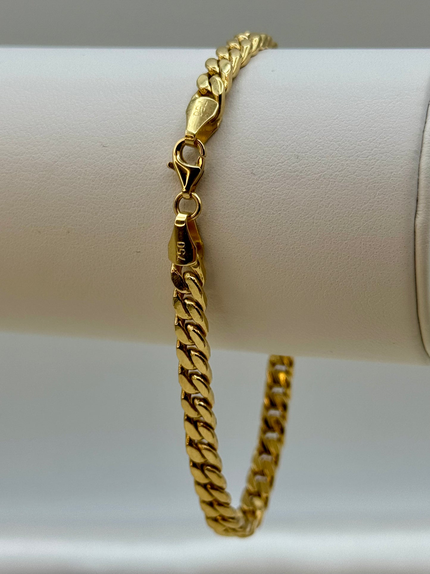 18k Gold chain bracelet on a white cylindrical object