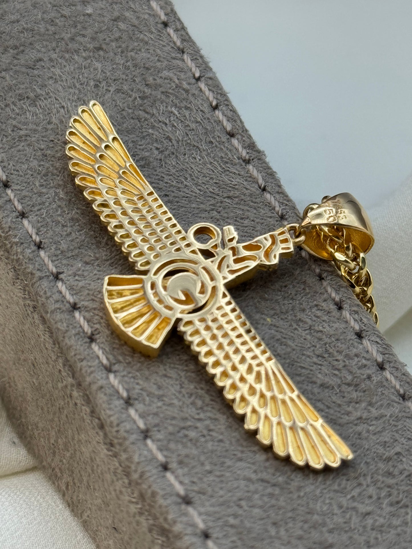 Gold eagle pendant on a gray textured surface