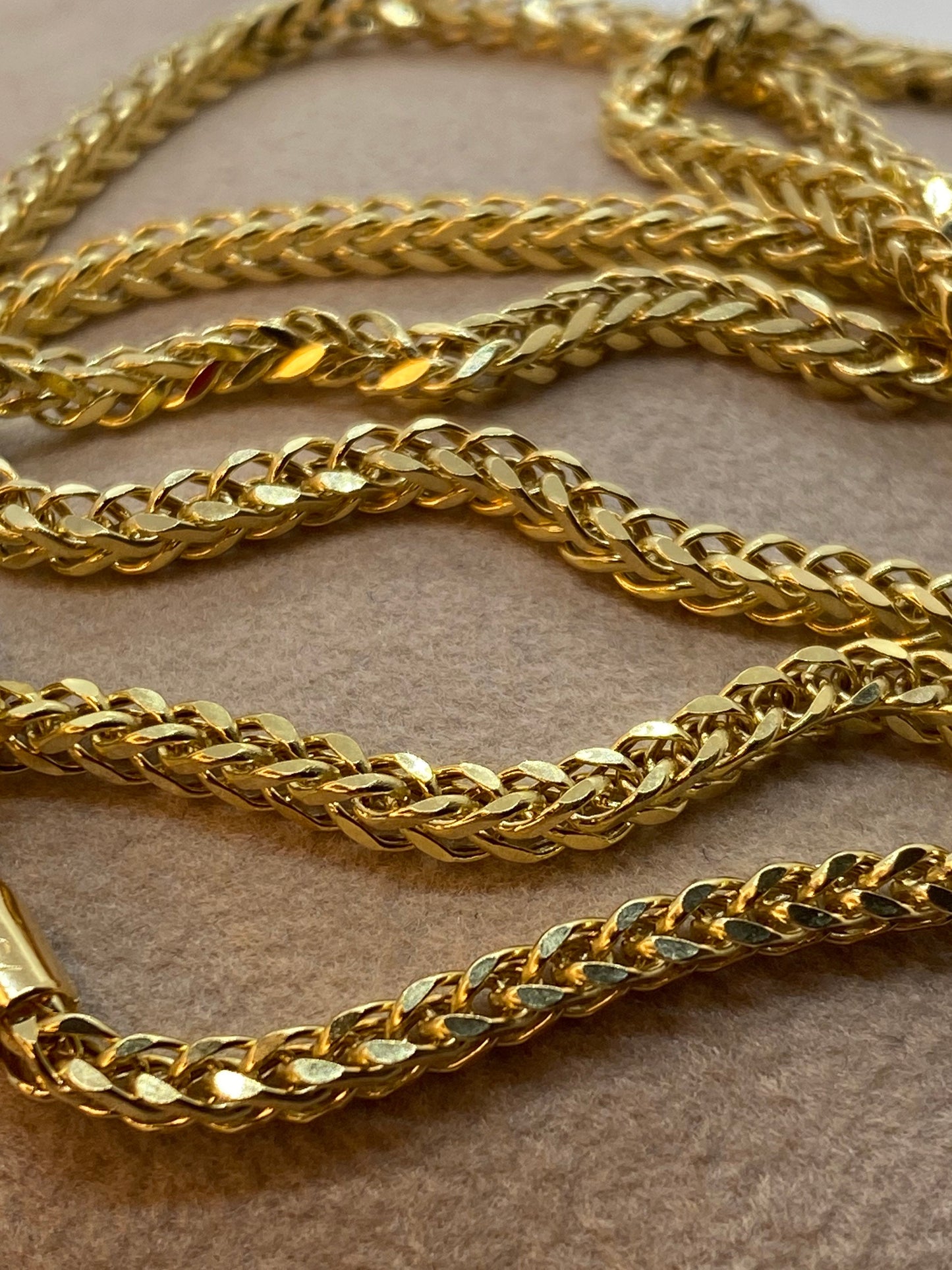 Close-up image of a 18k solid gold square Franco chain necklace with a foxtail link design.