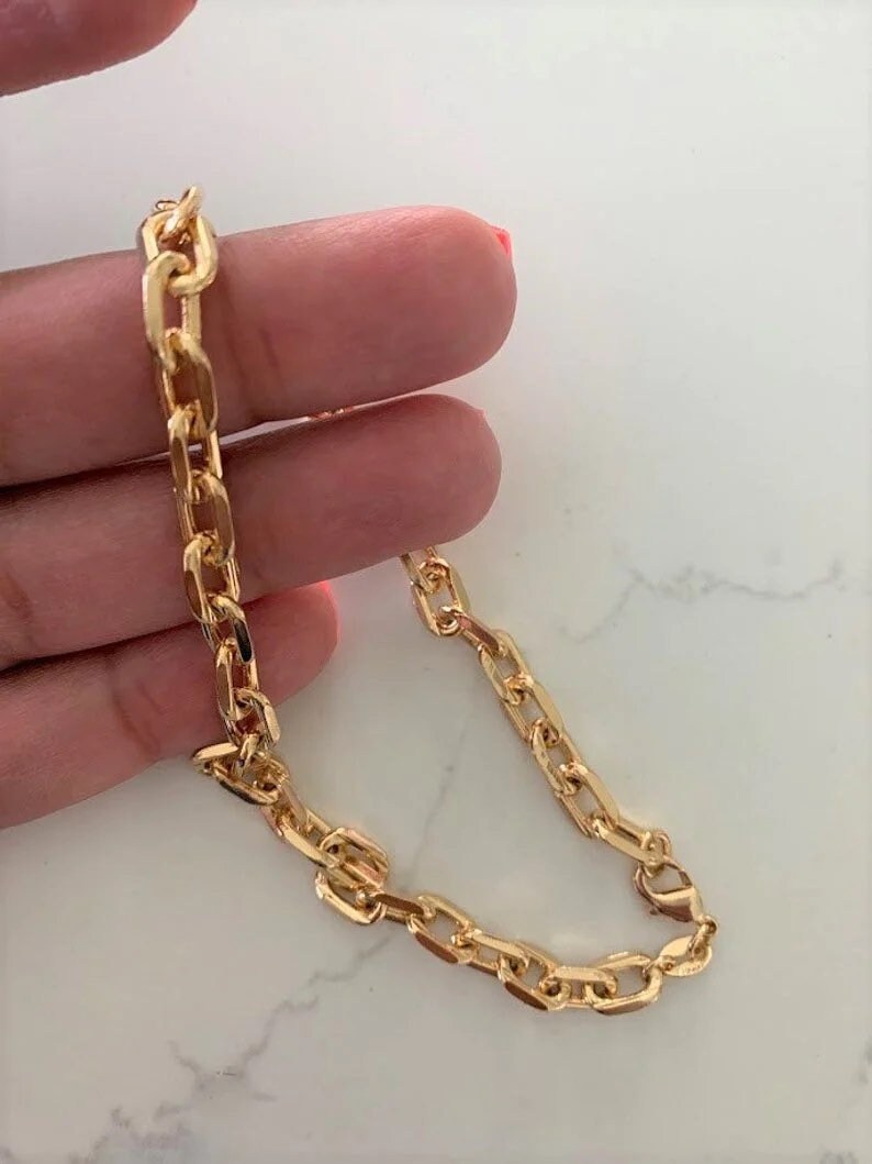 A 14K gold diamond-cut cable anklet on a person's hand, showcasing its gold color and lobster claw clasp.