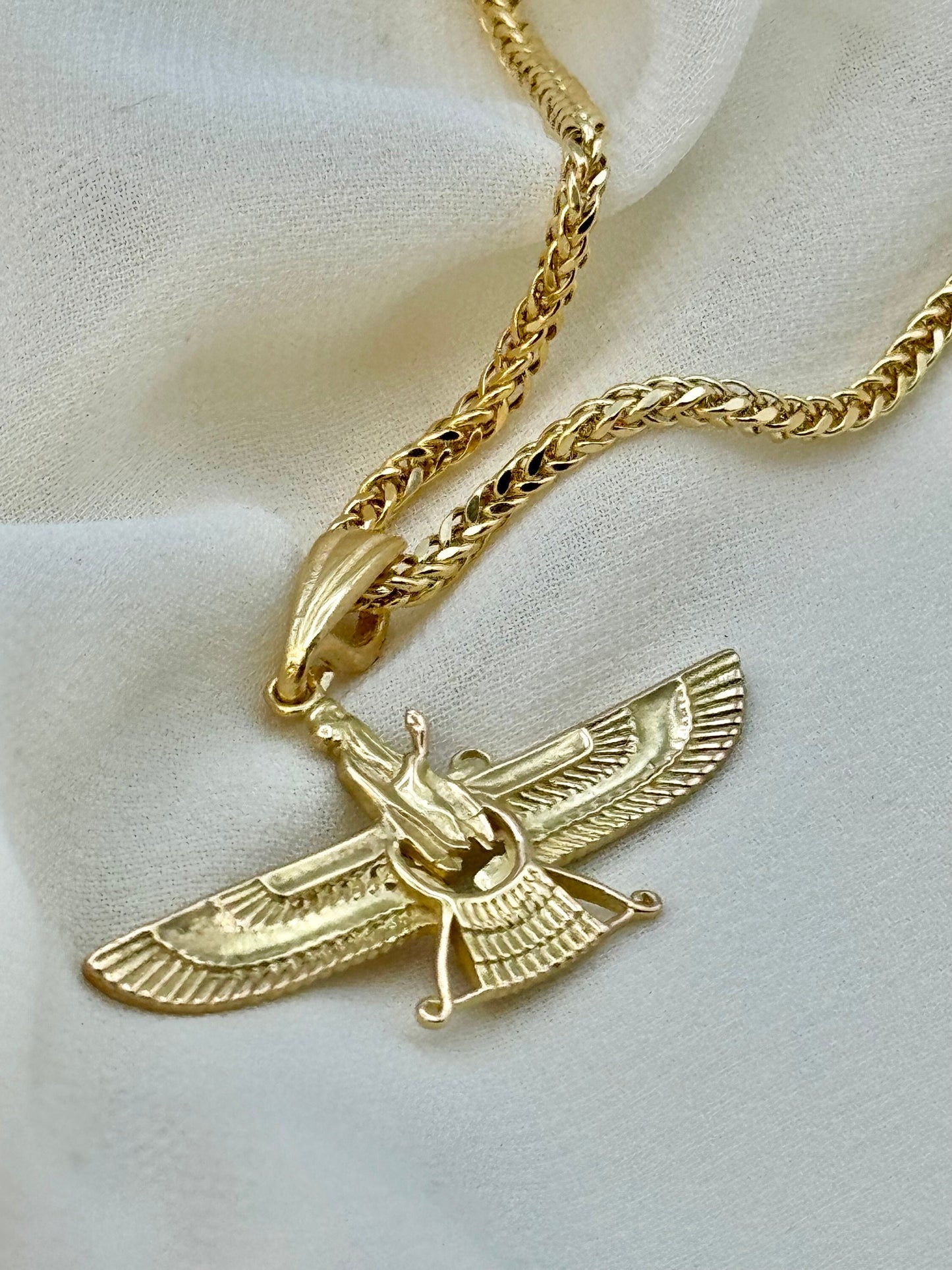 An 18K gold Faravahar pendant necklace displayed on a foxtail chain.