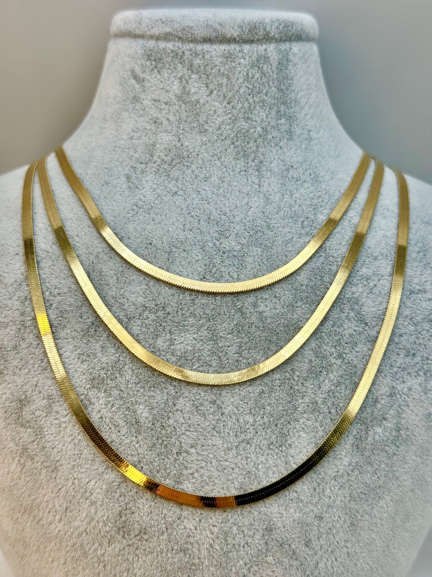18k gold herringbone design necklace and bracelet set on a mannequin bust