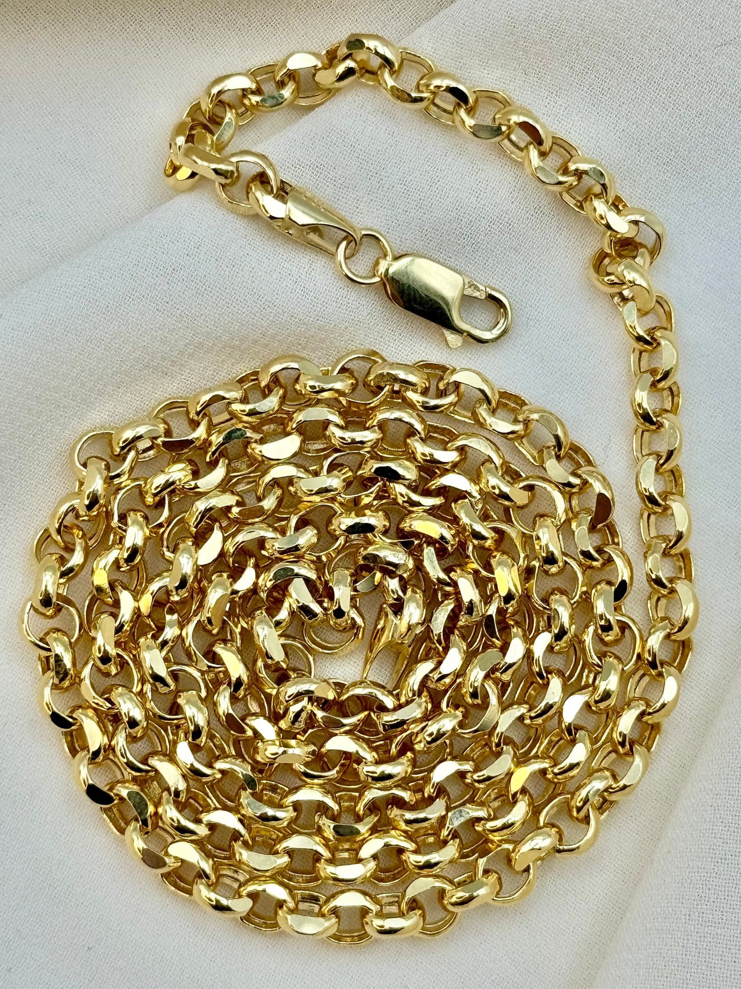 A coiled 14k gold rolo chain necklace with a lobster clasp, displayed on a white surface.