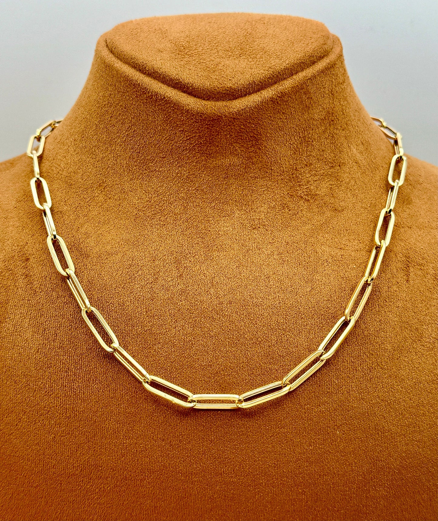 An 18k gold paperclip chain necklace displayed on a tan mannequin torso.