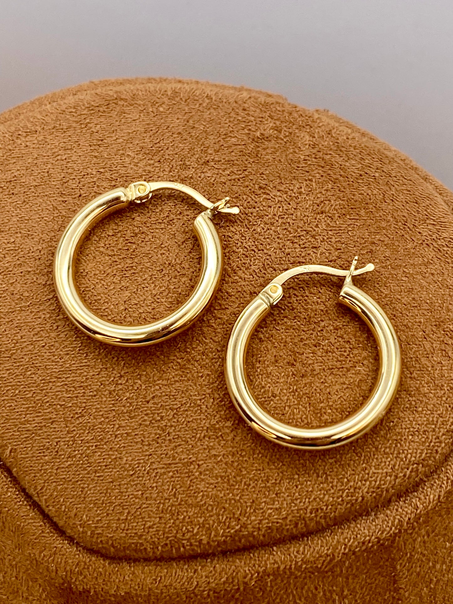 18k Gold hoop earrings on a brown textured surface