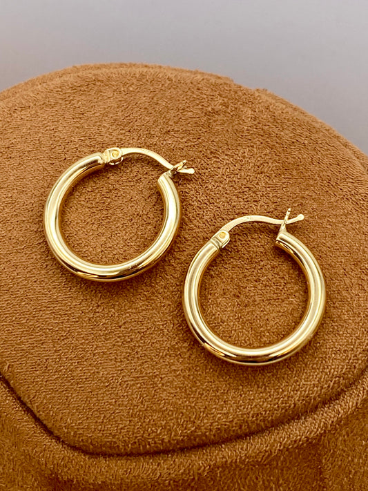 18k Gold hoop earrings on a brown textured surface