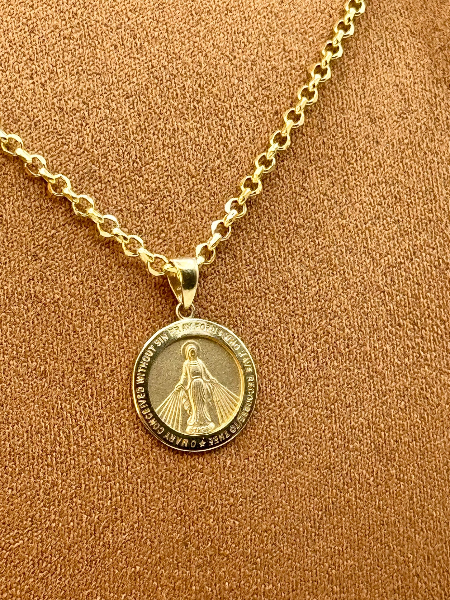 Gold necklace with a round virgin merry pendant on a brown background