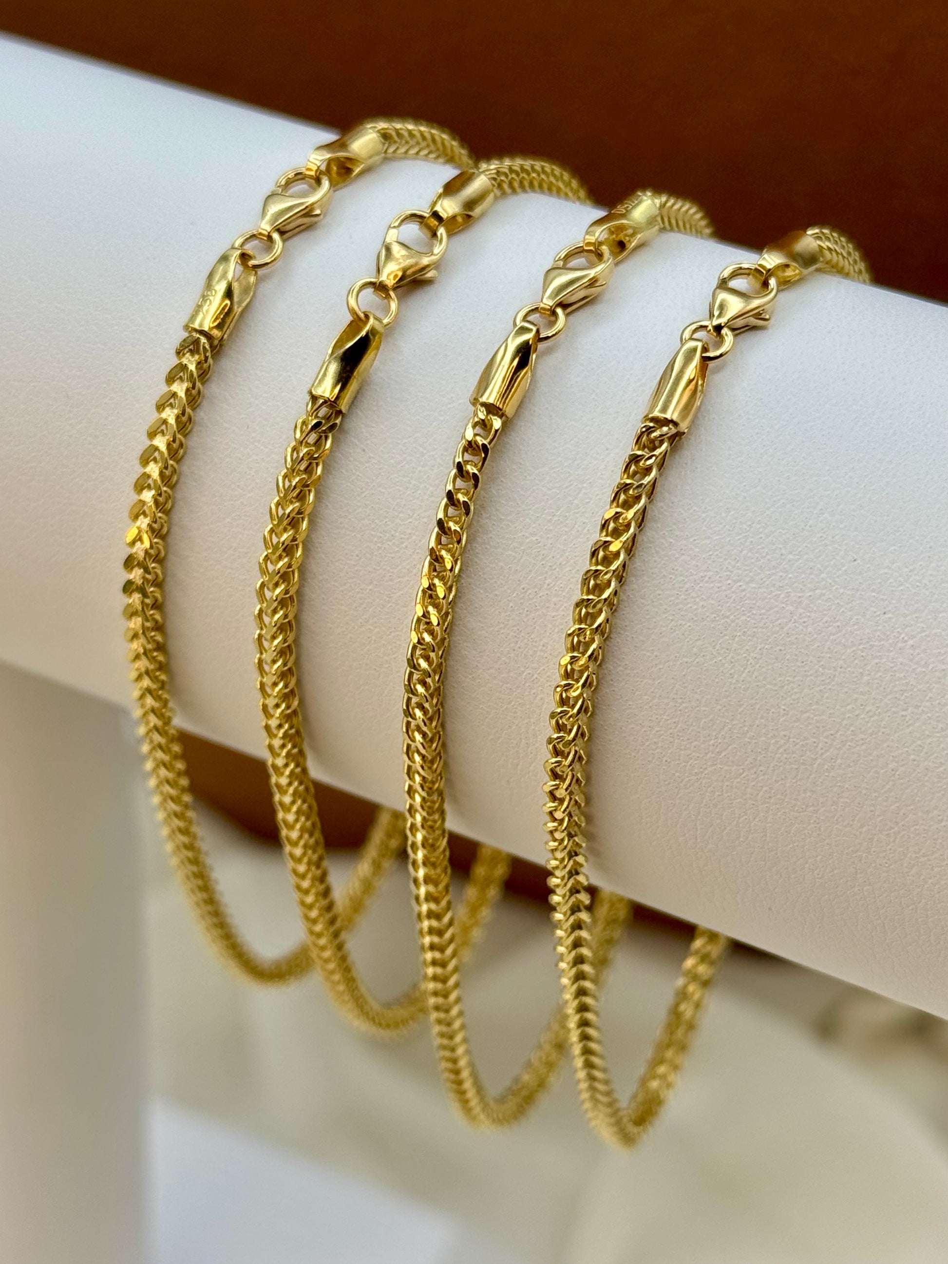 Three gold Franco bracelets on a white mannequin hand