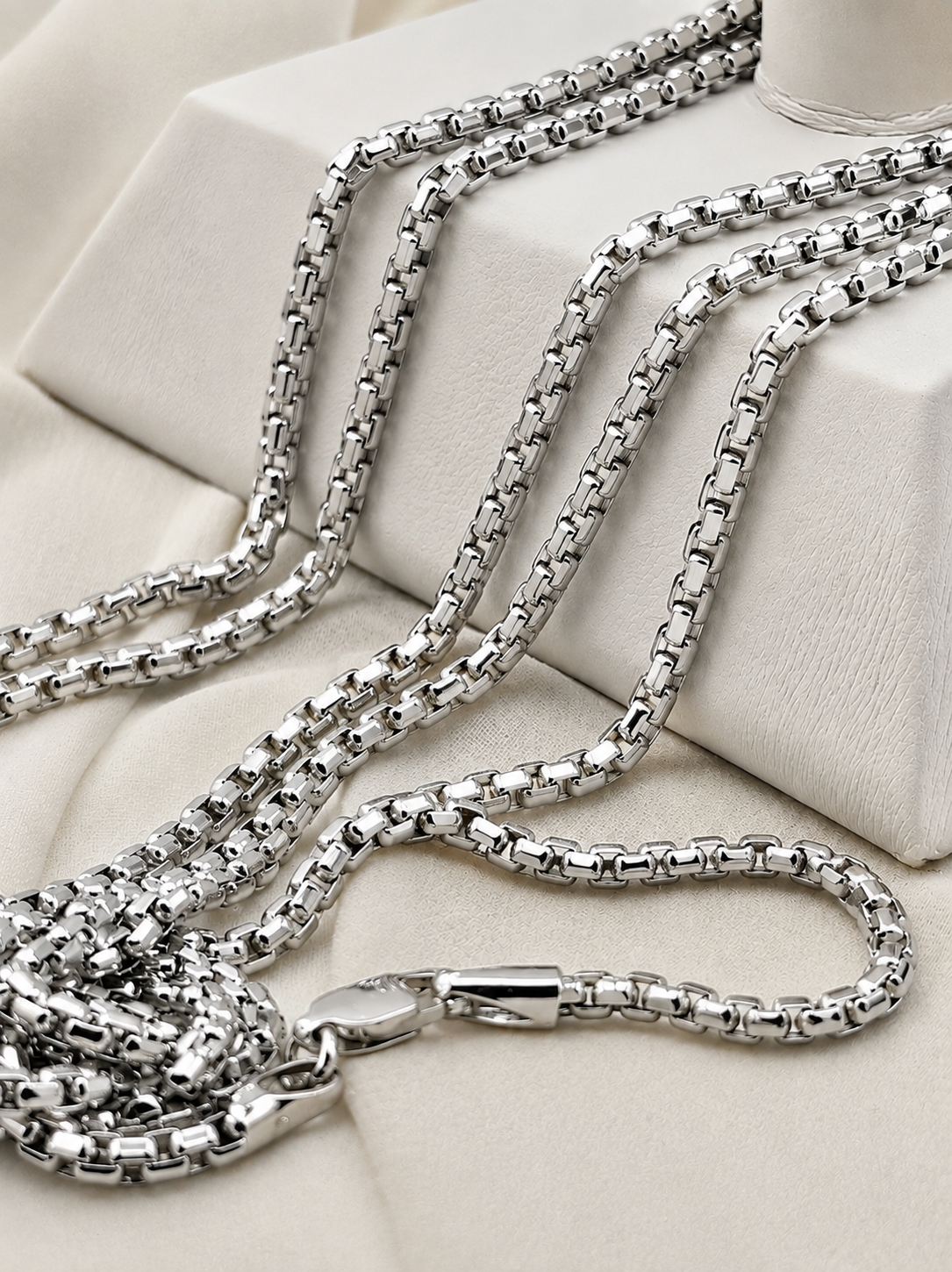 box chain necklaces in white colors on display.
