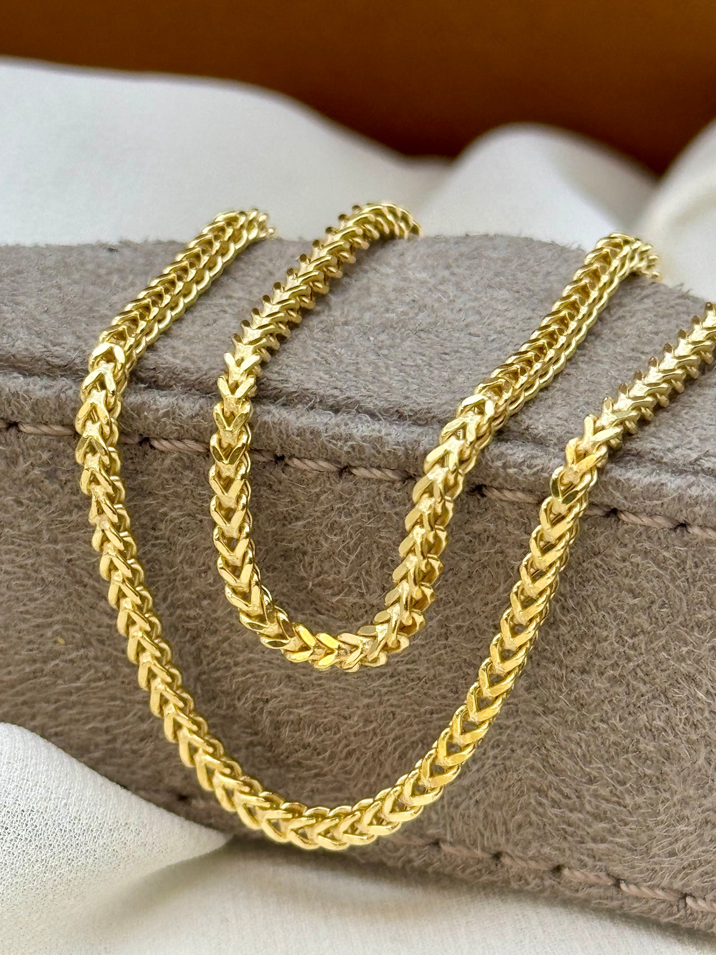 Three gold chains of different thicknesses on a textured surface