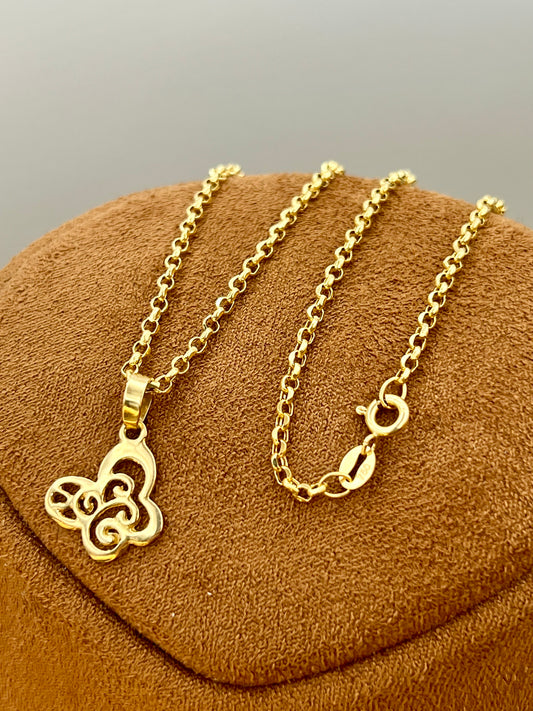 A gold-tone chain necklace with a butterfly pendant, displayed on a brown textured jewelry stand against a neutral gray background.