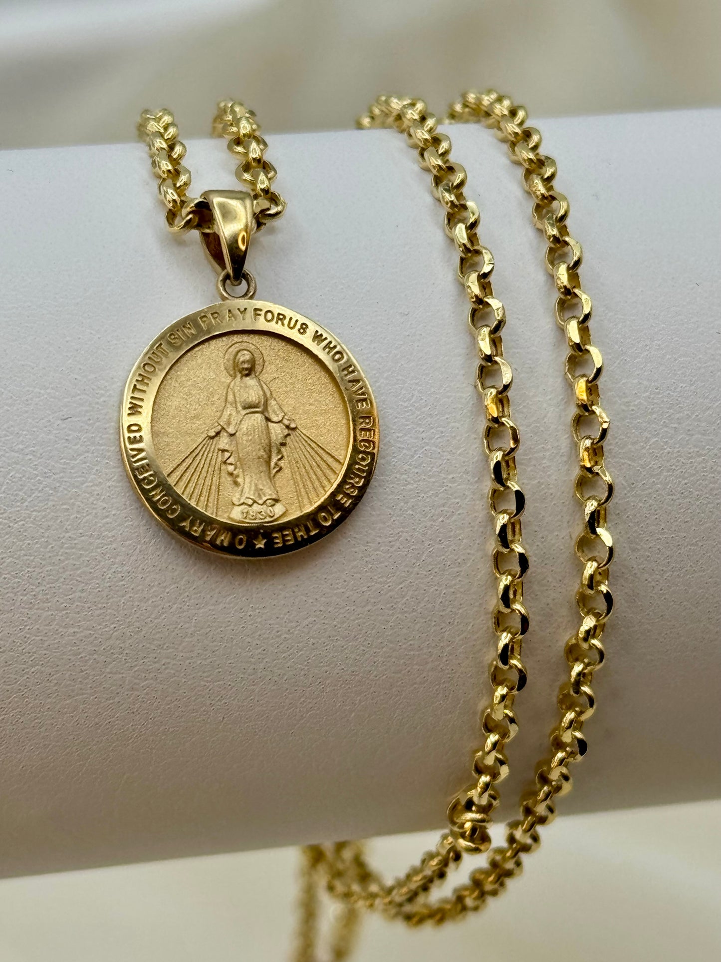 14k Gold virgin merry necklace with a medallion on a white surface