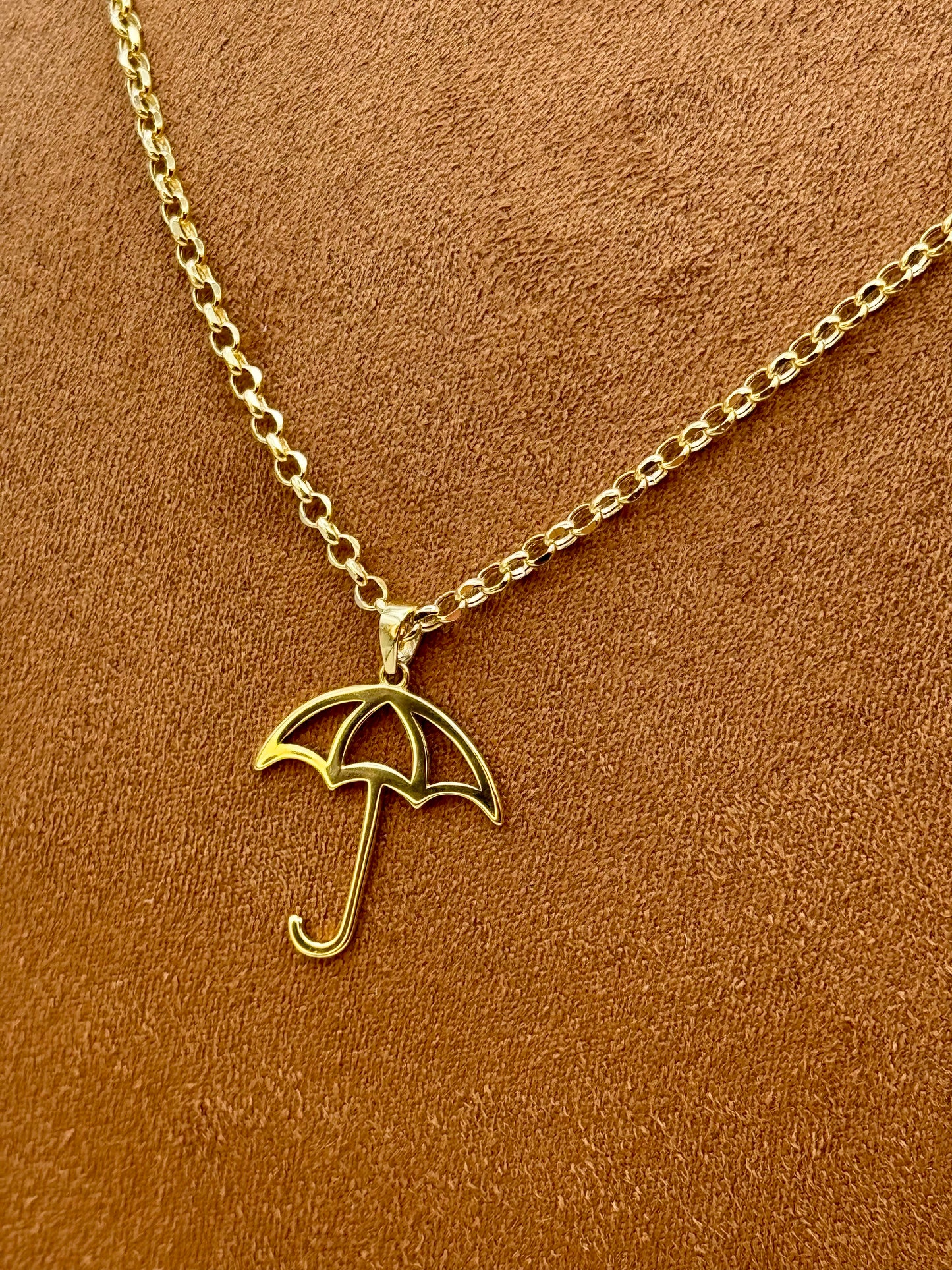 18k Gold umbrella necklace on a brown background