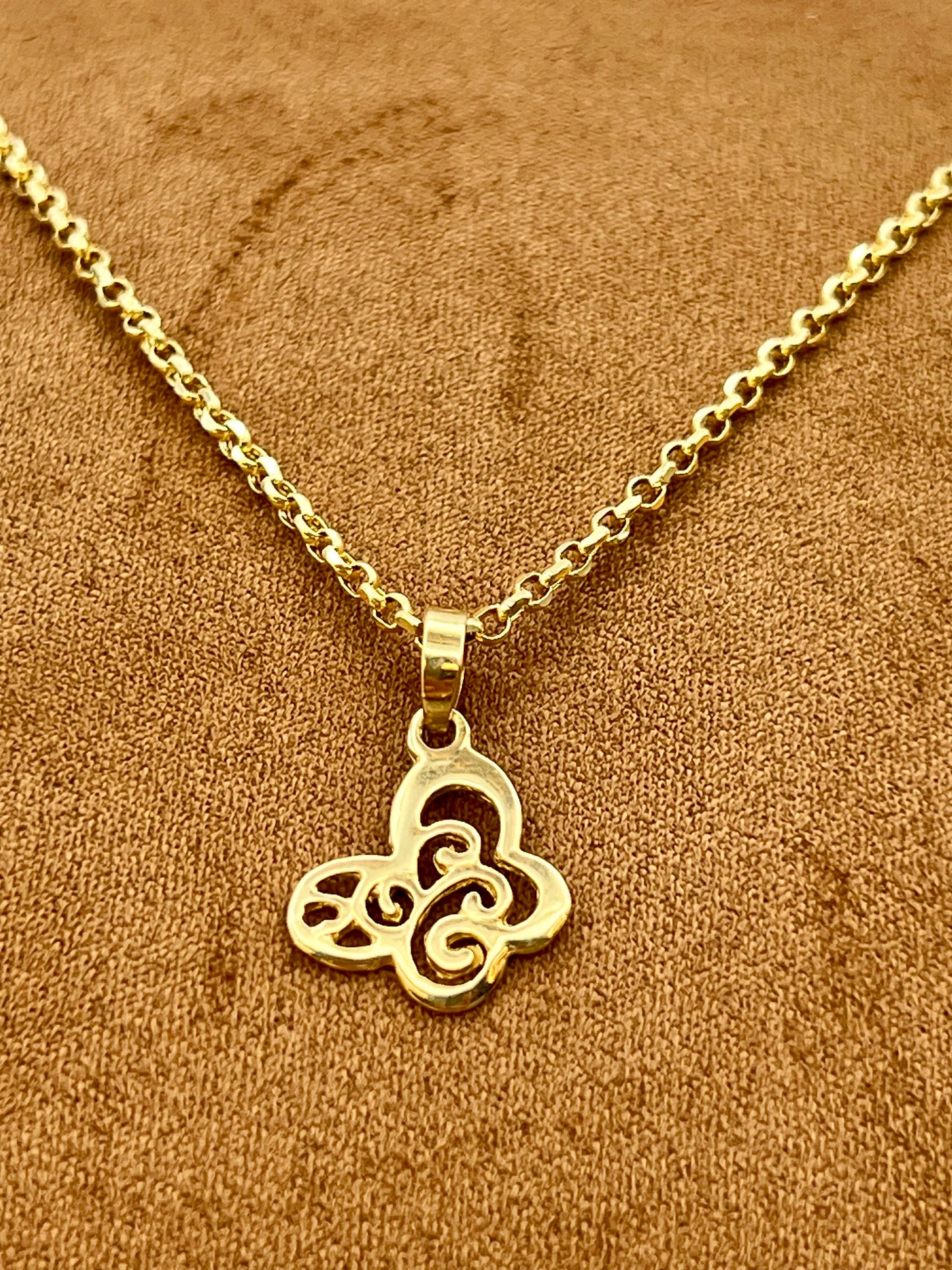 A gold-plated necklace with a Butterfly pendant, displayed on a textured brown fabric background.