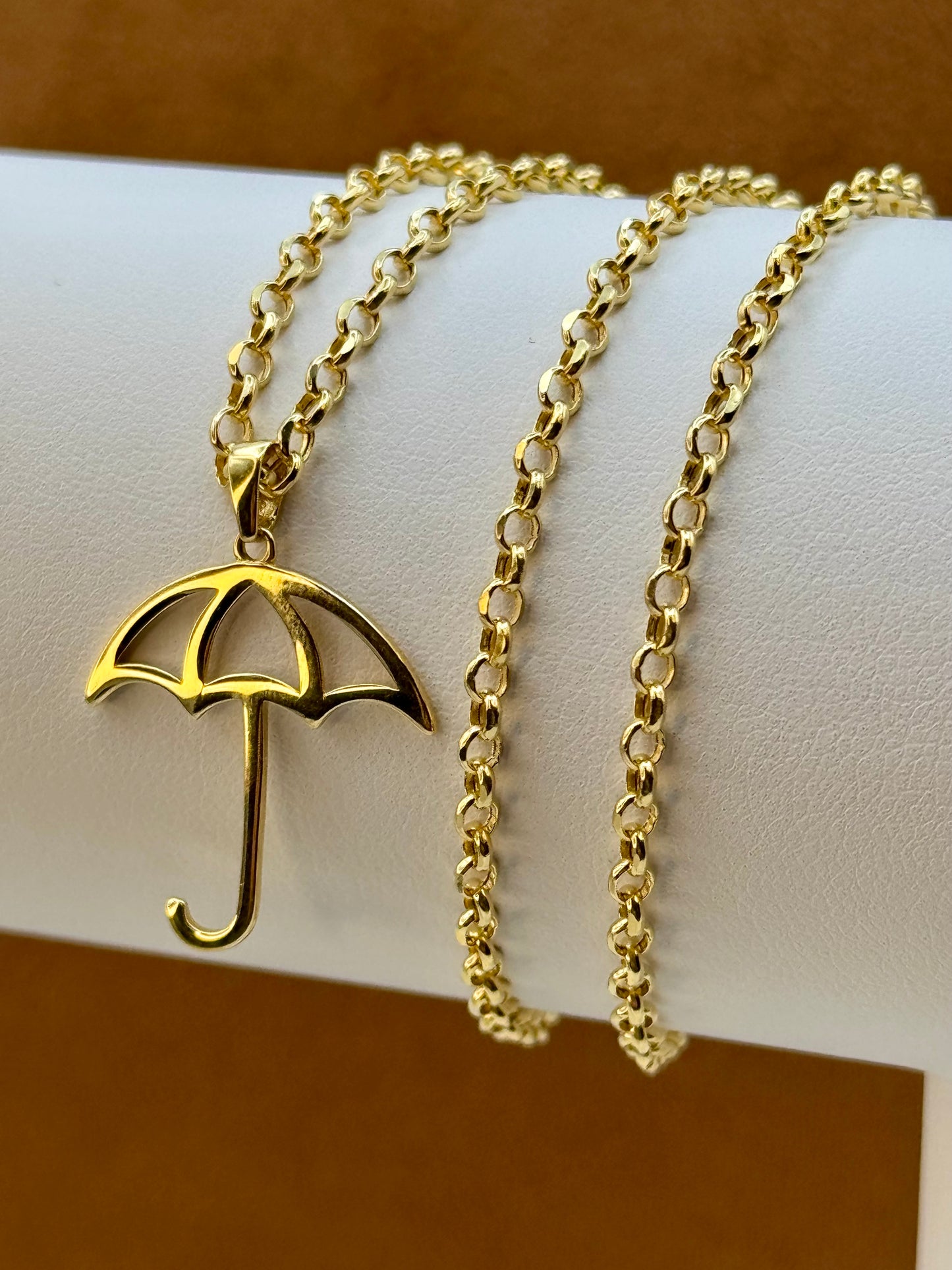 18k Gold necklace with an umbrella pendant on a white surface