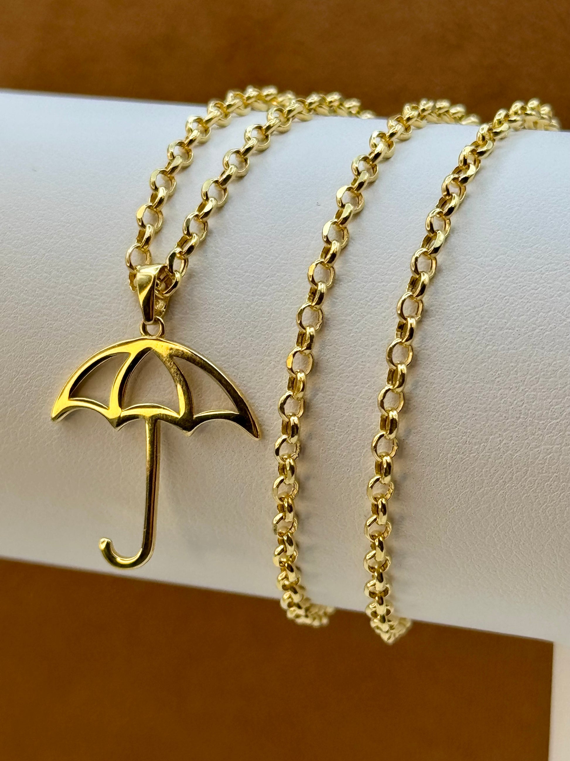 18k Gold necklace with an umbrella pendant on a white surface