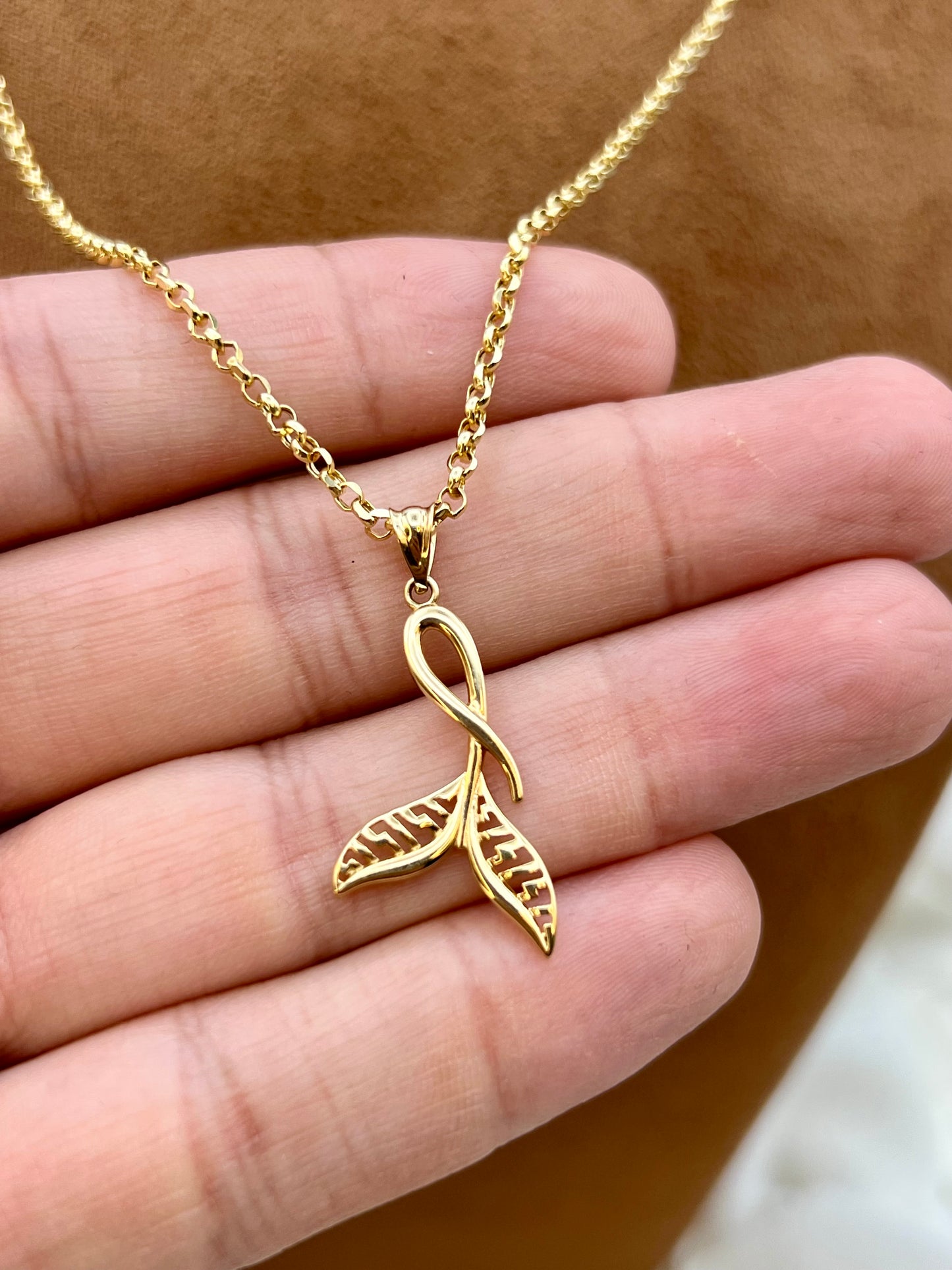 18k Gold whale tail  necklace on hand .