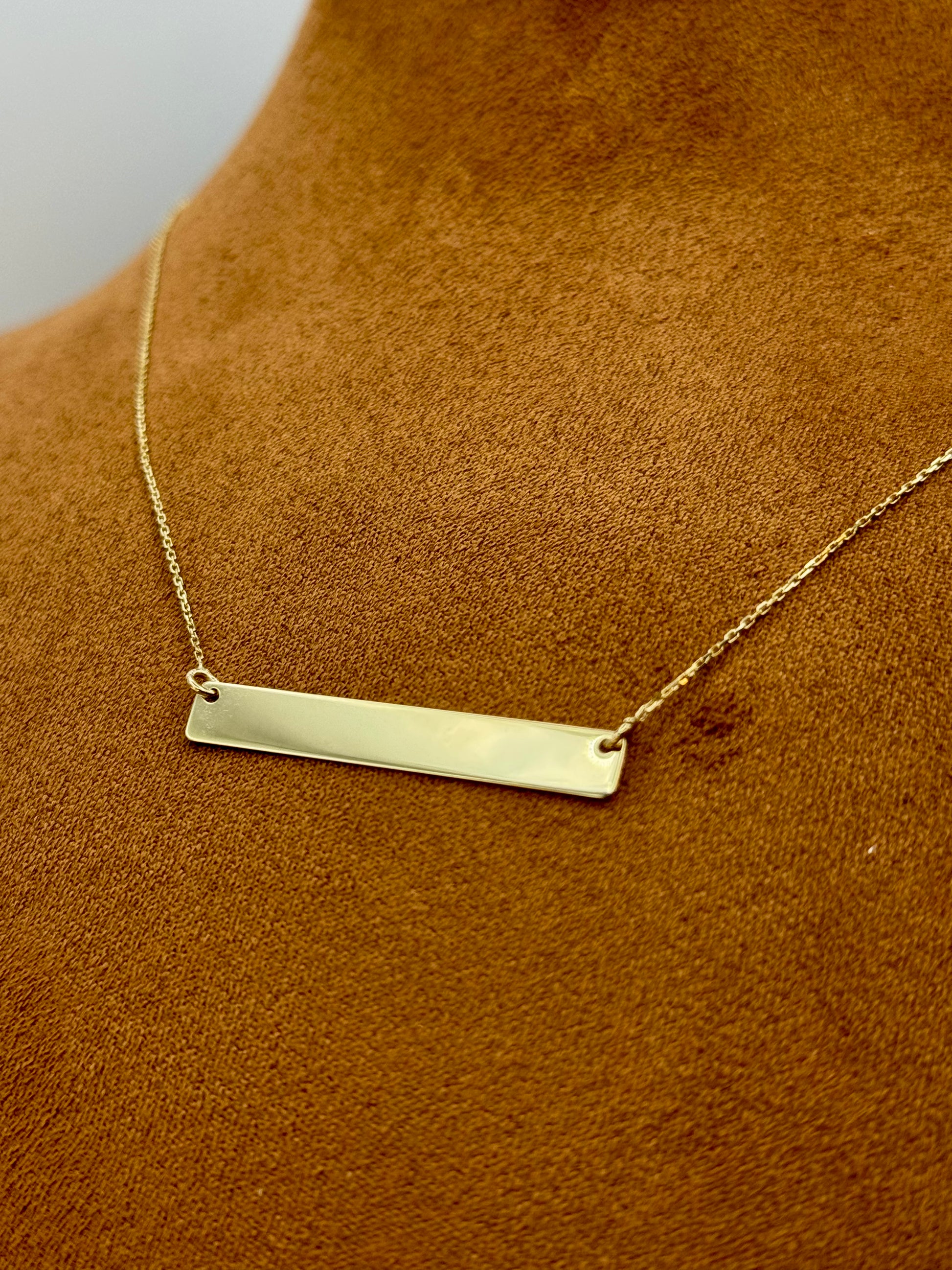 Gold bar necklace on a brown surface