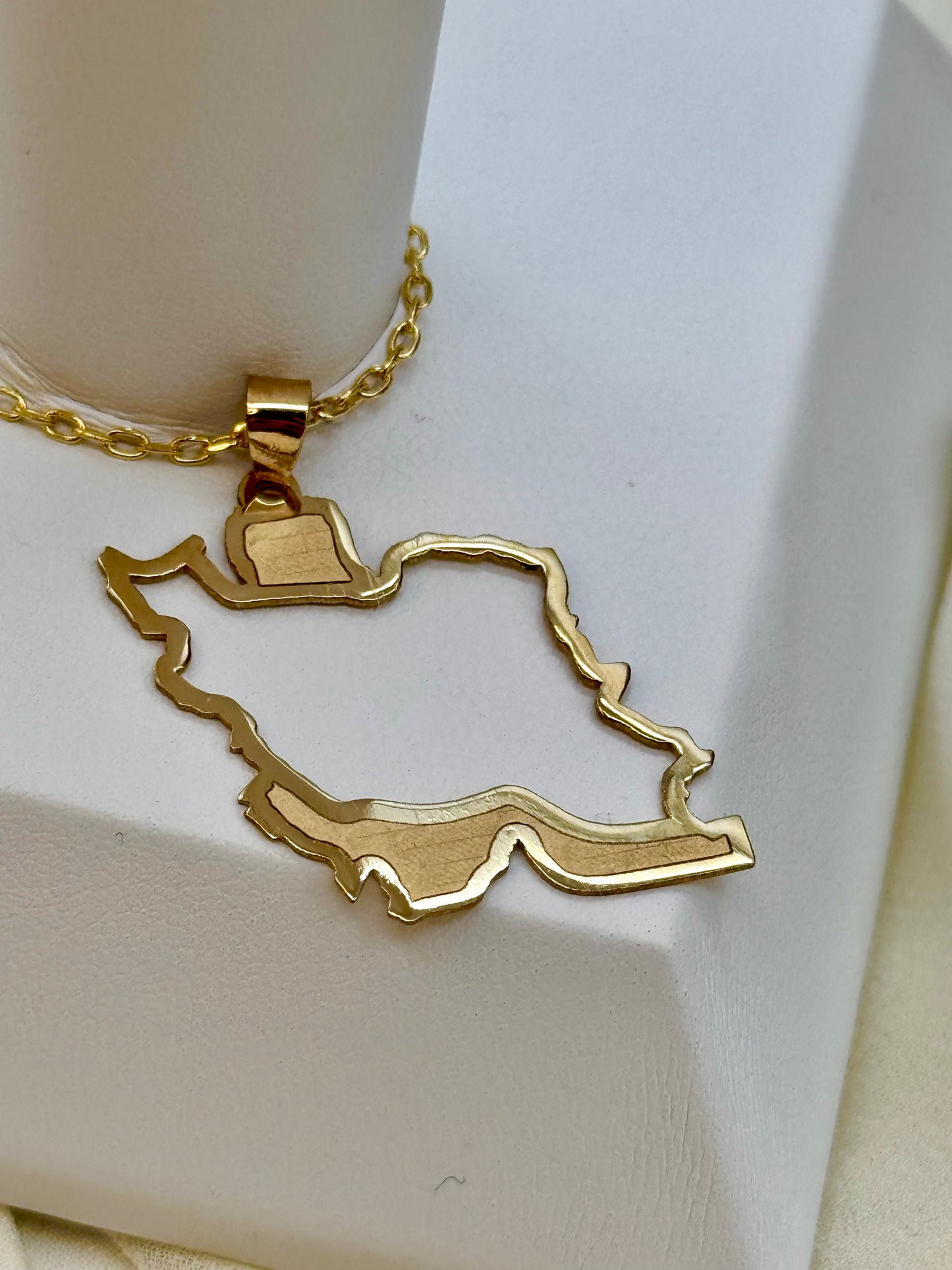 Gold necklace with a Iran map pendant on a white background