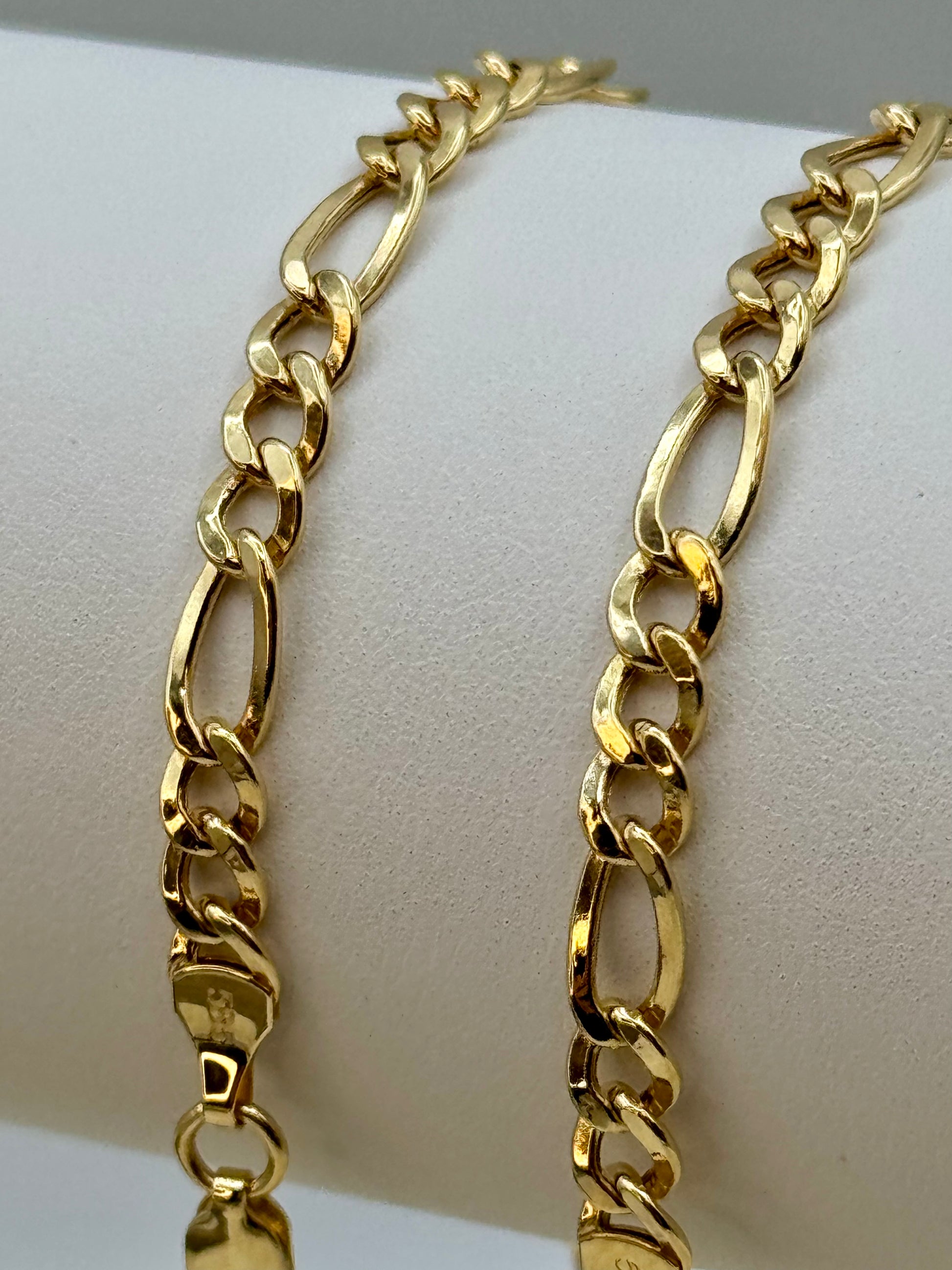 Gold chain bracelet on a white mannequin arm