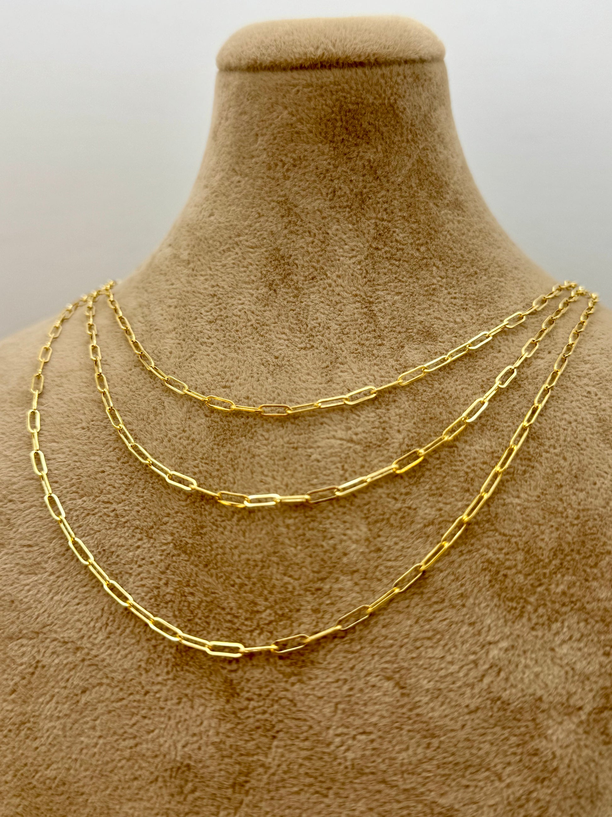 Gold chain necklace on a mannequin bust with a plain background