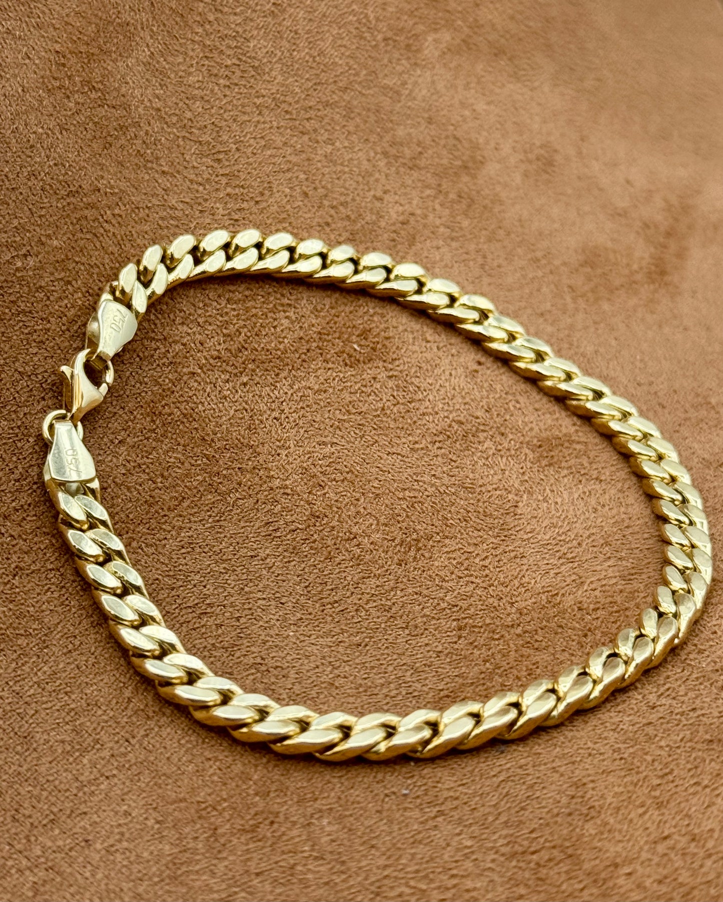 18k Gold curb bracelet on a brown textured surface