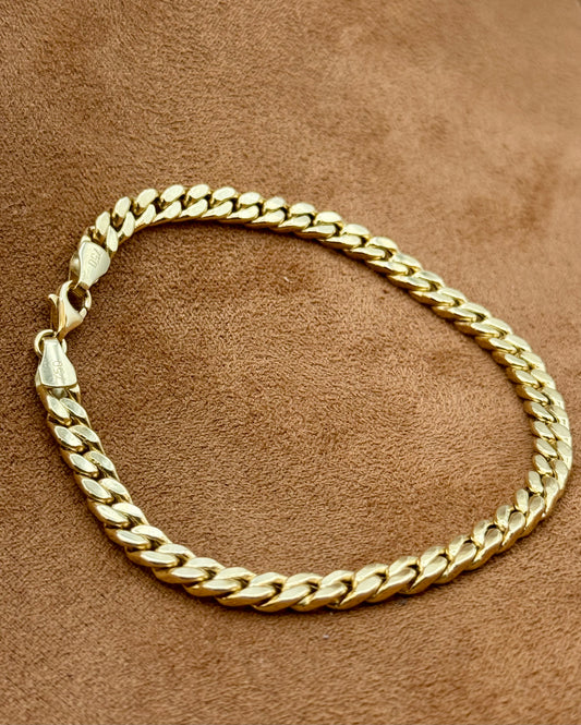 18k Gold curb bracelet on a brown textured surface