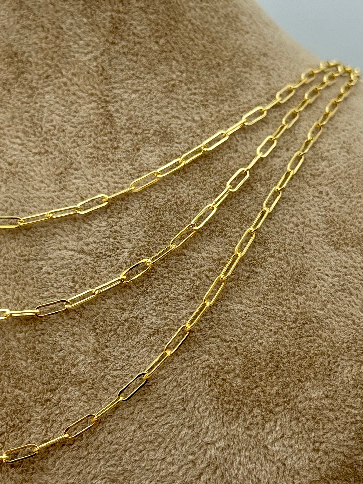 Gold chain necklace on a textured brown surface