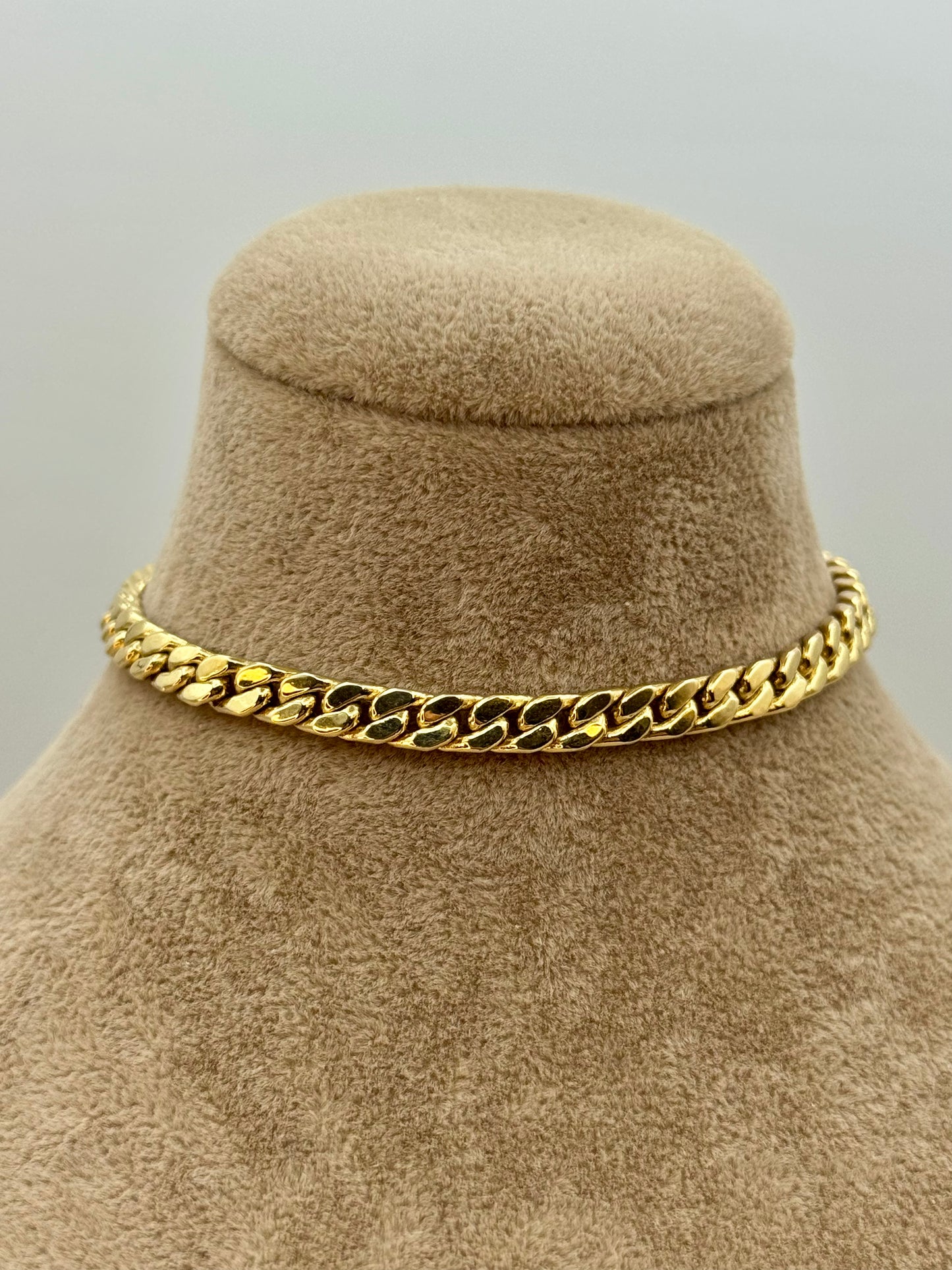 18k Gold chain bracelet on a beige mannequin bust against a gray background