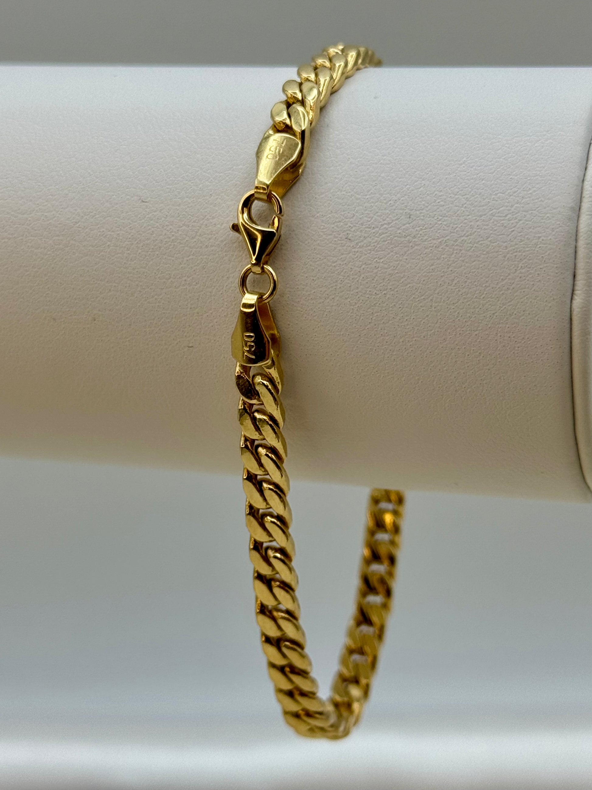 18k Gold chain bracelet on a white cylindrical object