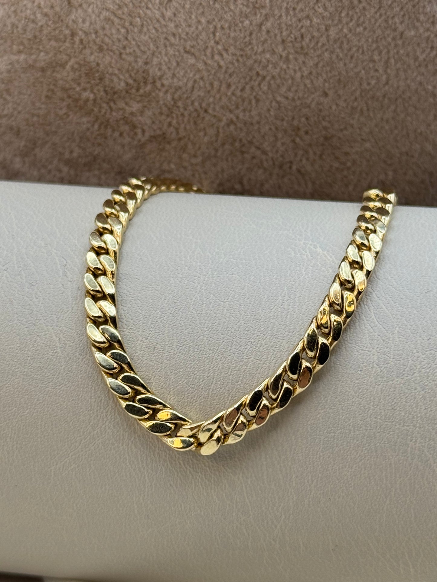 18k Gold chain bracelet on a light gray surface with a brown background