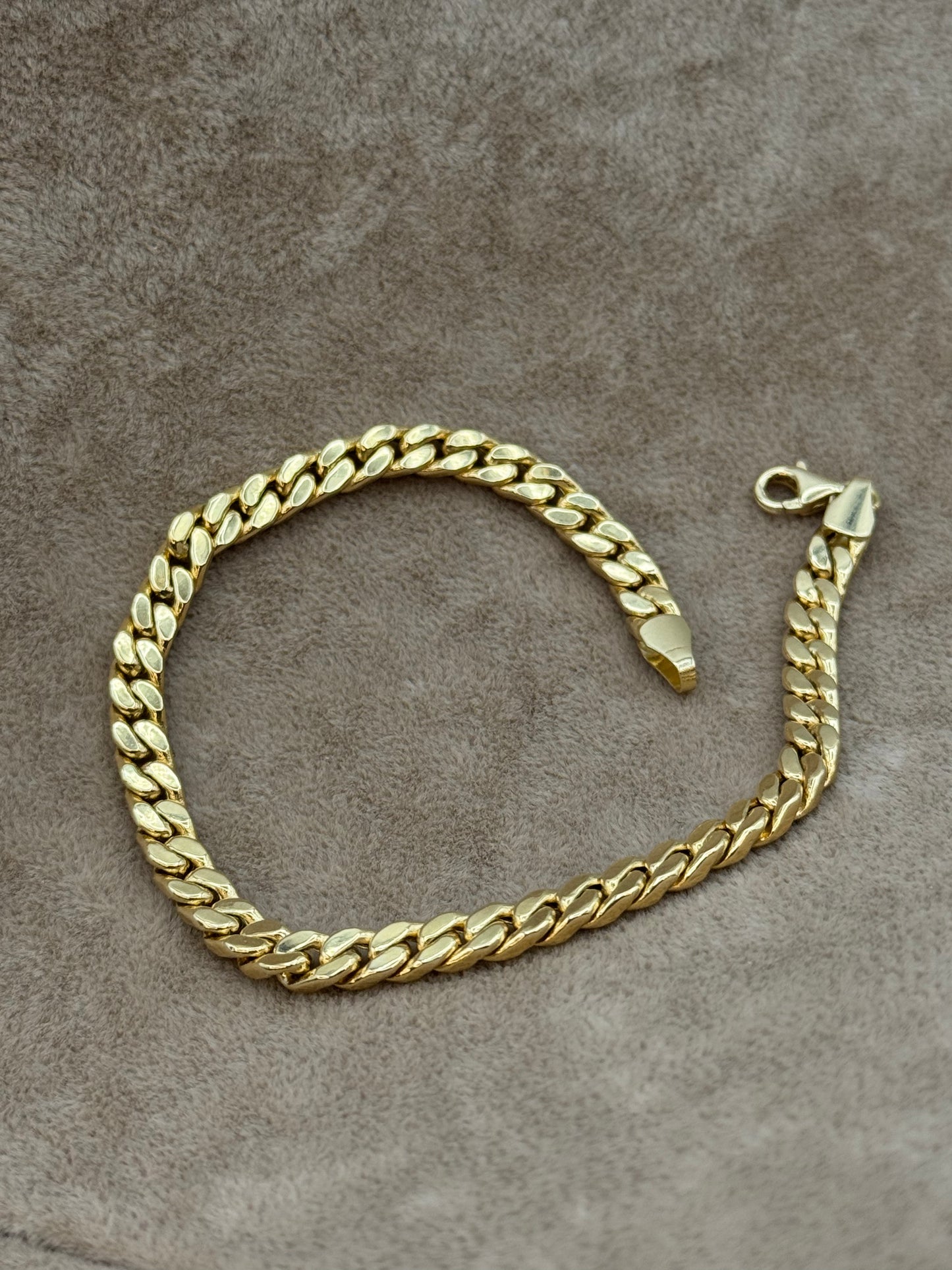 18k Gold curb chain bracelet on a textured brown surface