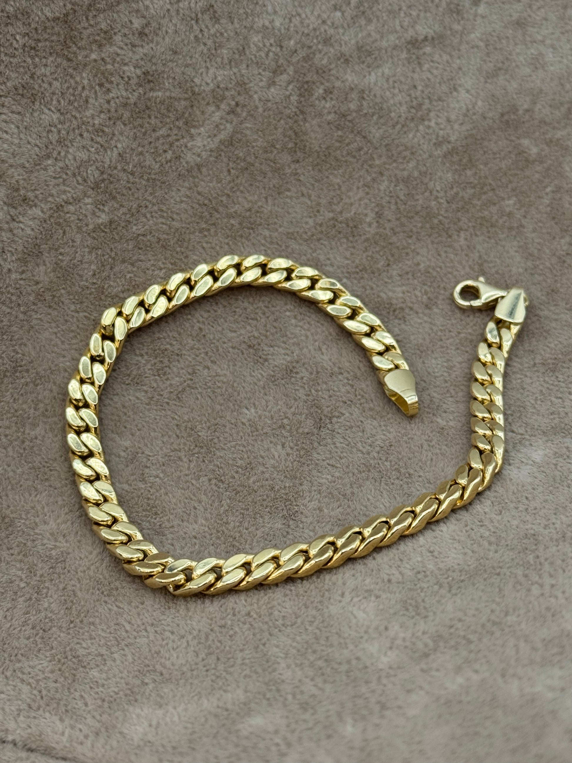 18k Gold curb chain bracelet on a textured brown surface