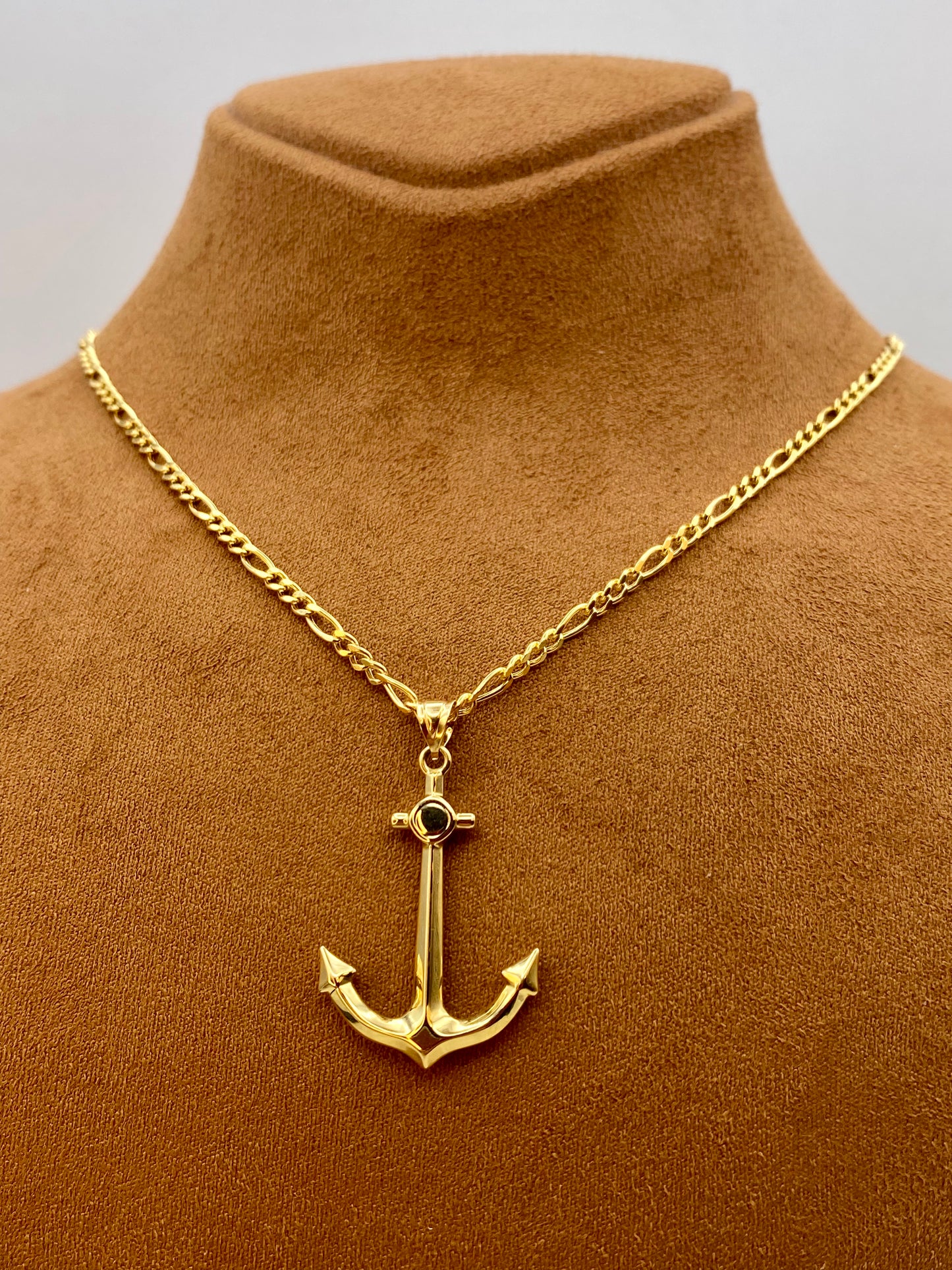 Gold anchor necklace on a brown mannequin