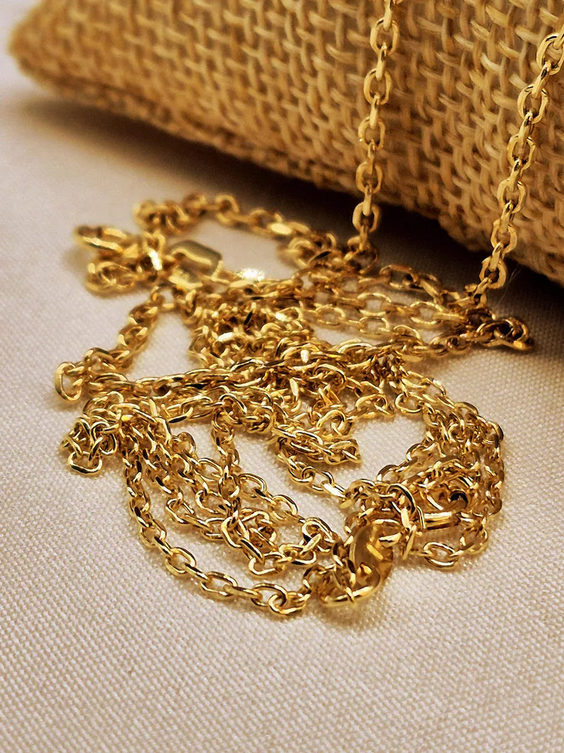 Gold chain necklace on a textured beige surface