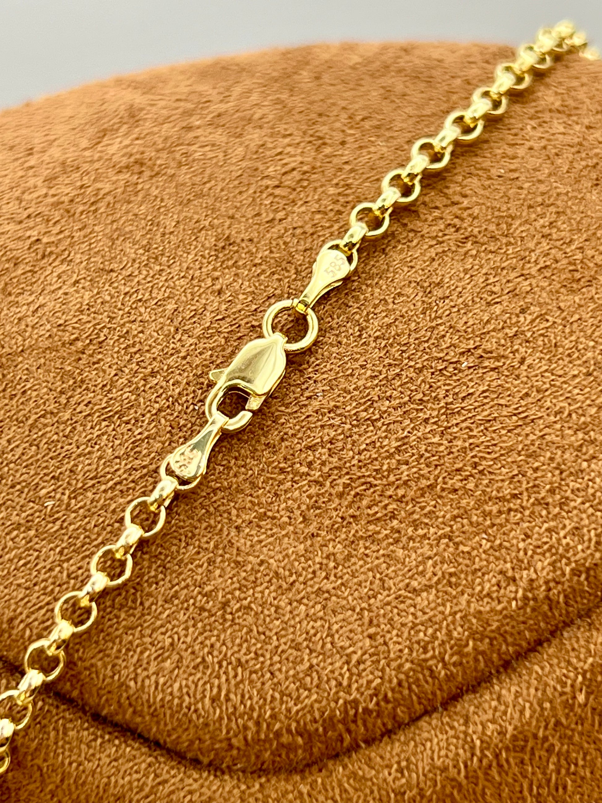A close-up of a gold chain bracelet with a lobster clasp, displayed on a textured brown velvet jewelry stand.