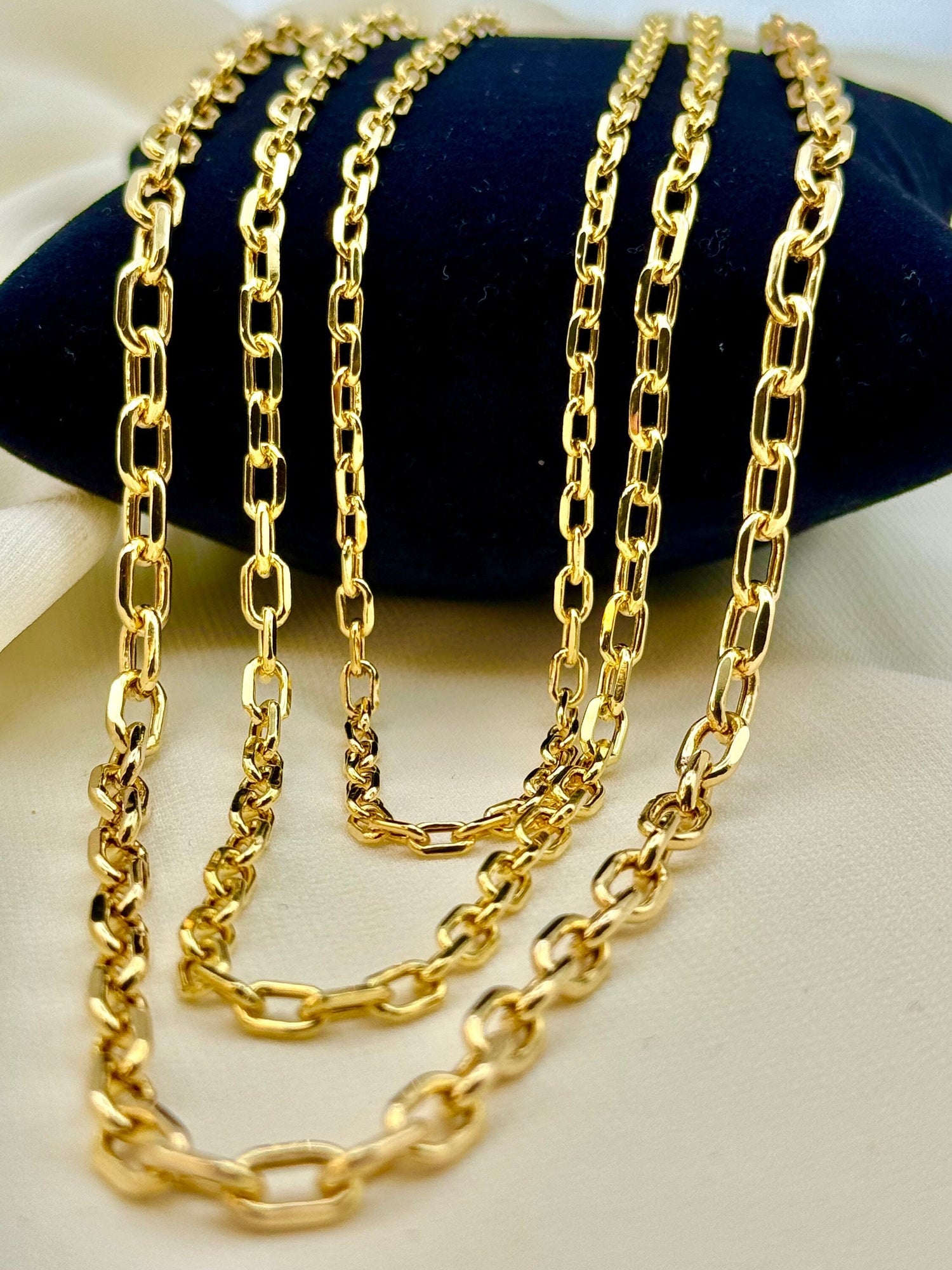 A 14k gold cable chain necklace laid out on a surface, displaying its textured and link design.
